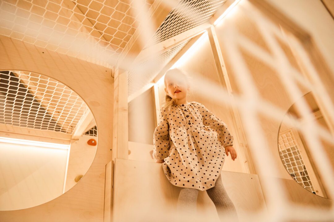 Dziewczynka stoi w środku małpiego gaju, widoczne są estetyczne siatki zabiezpiezające