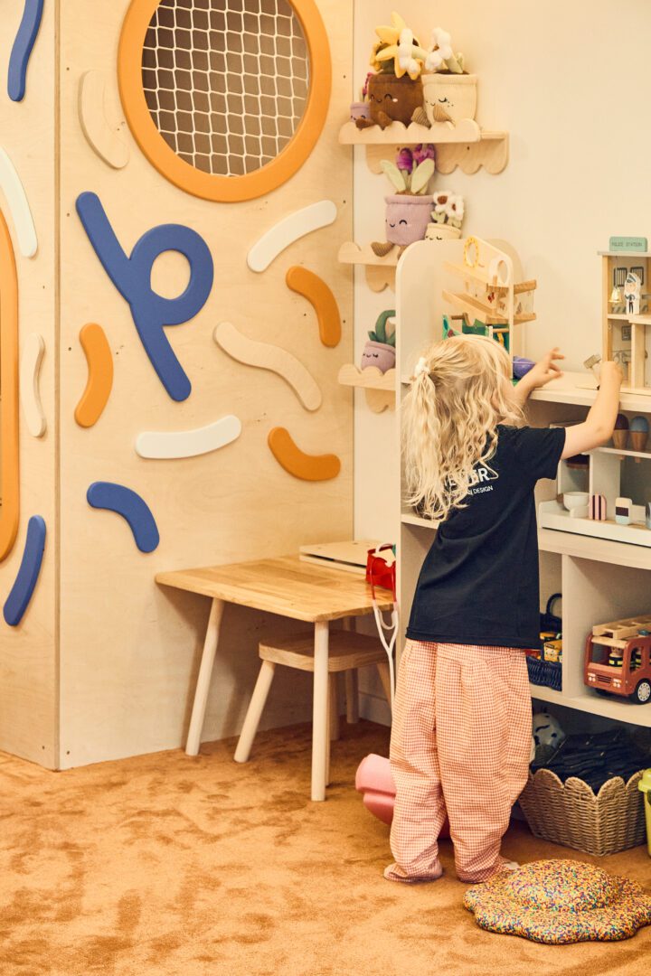 dziewczynka bawi się drewnianymi zabawkami, stoi obok małpiego gaju